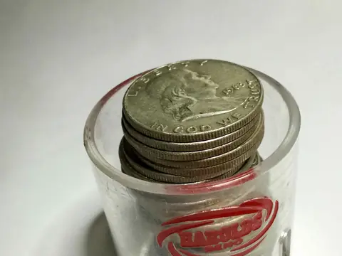 A stack of 1963 Franklin half dollars in a clear round coin holder