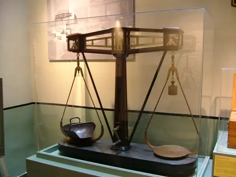 A large old coin scale in a glass case at the New Orleans Mint