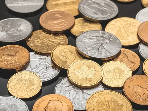 American Silver Eagles and Canadian Silver Maple Leafs among gold bullion coins on a dark glossy table